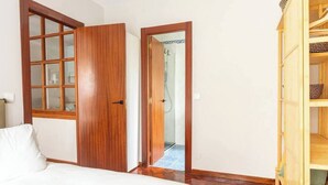 Un dormitorio con cama, armario de madera y puerta que da a un baño.