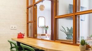 A kitchen with a wooden countertop, green chairs, and a window with multiple panes.