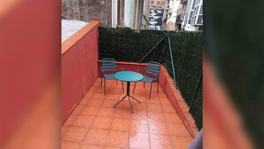Un piccolo patio esterno con pavimento piastrellato, un tavolo rotondo e due sedie.