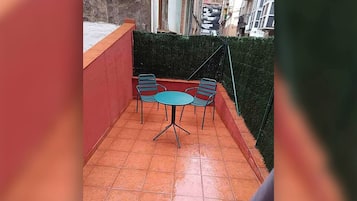 A small outdoor patio with a tiled floor, a round table, and two chairs.