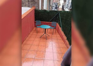A small outdoor patio with a tiled floor, a round table, and two chairs. - Moderno y cómodo apartamento en el centro (Santander)