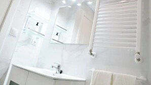 Een moderne badkamer met een wit wastafelmeubel, een spiegel en een handdoekrek.