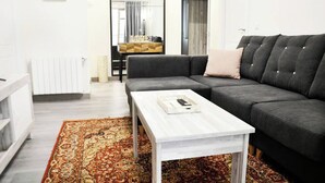 Een moderne woonkamer met een grijze bank, een witte salontafel en een kamerbreed tapijt met een patroon.