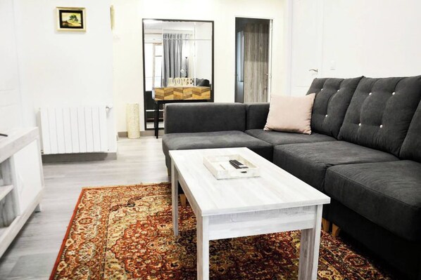 A modern living room with a grey sofa, a white coffee table, and a patterned rug.