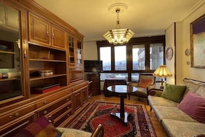 Una sala de estar con un mueble grande de madera, un sofá, una mesita redonda y una araña.