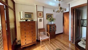 A room with a wooden dresser, a chair, a cabinet, and a ceiling fan. - Elegante apartamento con vistas al puerto (Santander)