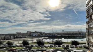 A parking lot with cars and a body of water in the background. - Elegante apartamento con vistas al puerto (Santander)