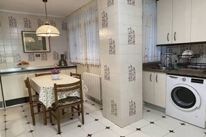 A compact kitchen with a dining area, a washing machine, and a radiator. - Elegante apartamento con vistas al puerto (Santander)
