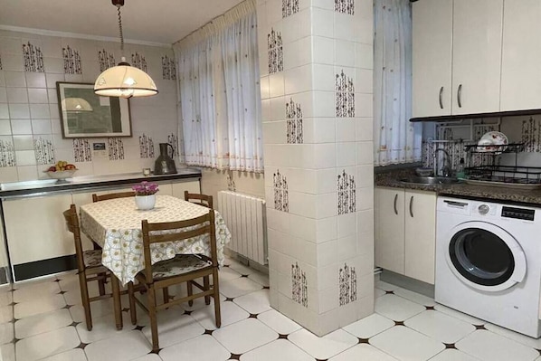 Una cocina compacta con zona de comedor, lavadora y radiador.