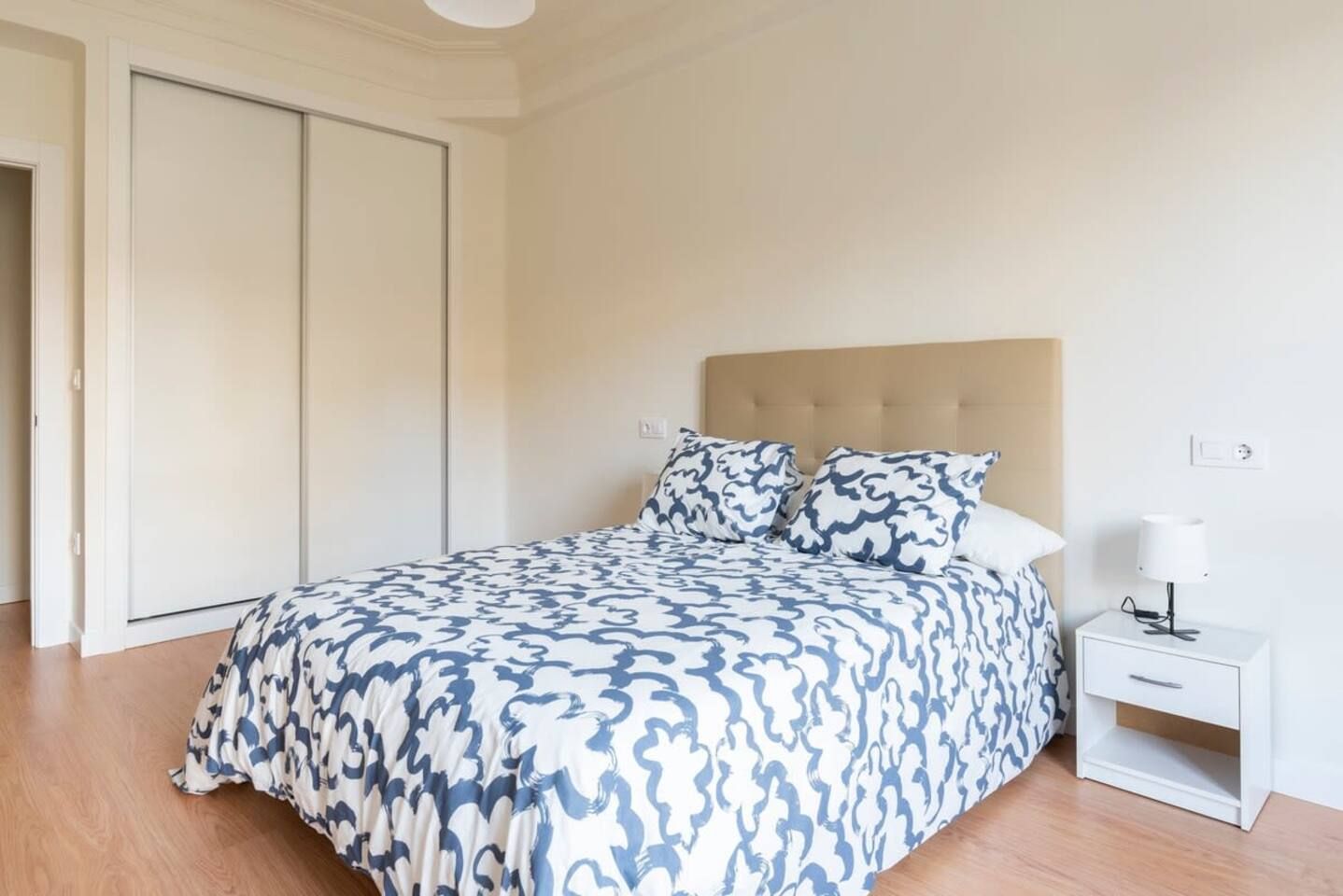 Un dormitorio con cama, mesita de noche y armario.