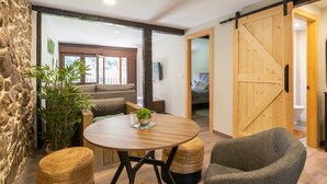 A cozy room with a round wooden table, a gray armchair, and a large wooden door.