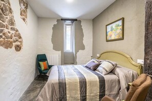 A bedroom with a bed, a chair, a painting, and a window. - El Cason Riva Ruesga (Riva)
