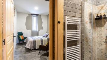 Une chambre à coucher comprenant un lit, une chaise, un radiateur et un espace douche avec un mur carrelé.