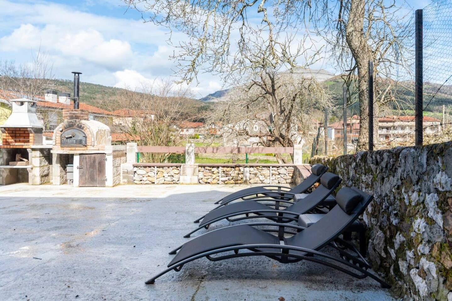 Terraza al aire libre con muro de piedra y vista a un pueblo.