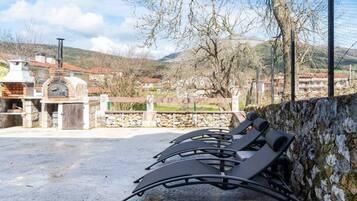 Terraza al aire libre con muro de piedra y vista a un pueblo.