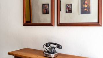 A wooden desk with a vintage telephone and two framed pictures on the wall above.