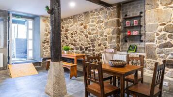 Una habitación con paredes de piedra, una mesa de madera y sillas, un banco y una puerta con la etiqueta 'SALIDA'.