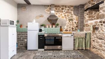 Una cocina compacta con pared de piedra, microondas, refrigerador, estufa y lavavajillas.