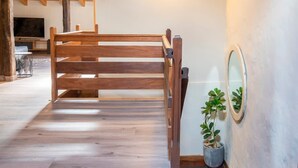 A wooden bench in a room with a sloped ceiling and stone wall.