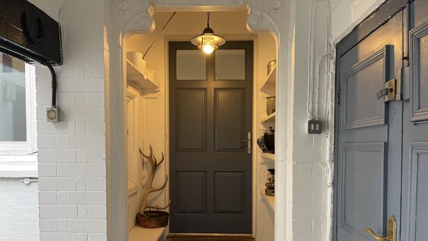 A narrow hallway with a dark door, a light fixture above, and a rustic antler decoration on the wall. - 1bedapt Privateestate W/free Parking - 10mintocity (Nottingham)