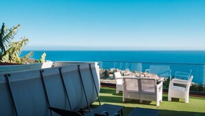 A terrace with white wicker furniture, a white boat, and a view of the ocean. - GuestReady - Sonho dos Avós I (Câmara de Lobos)