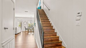 A staircase with wooden steps and a metal railing leading to a dining area with a table and chairs.
