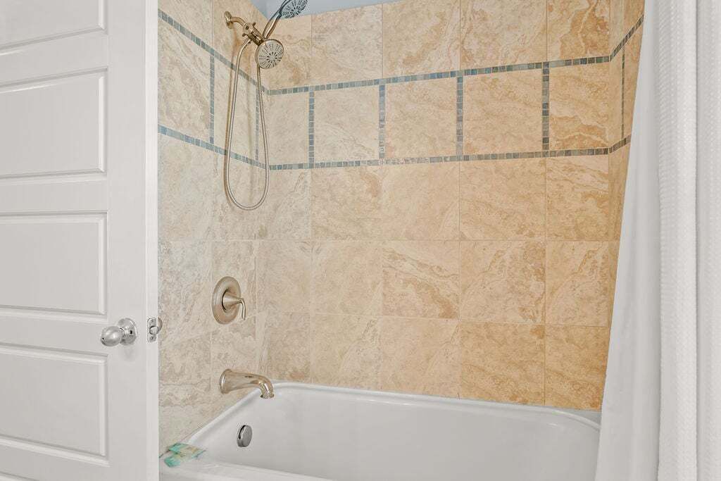 Ein Badezimmer mit Badewanne, Duschkopf und Fliesenwand.