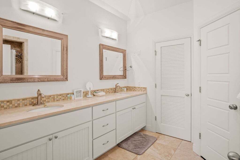 Un bagno con un lavabo doppio, uno specchio e una porta.