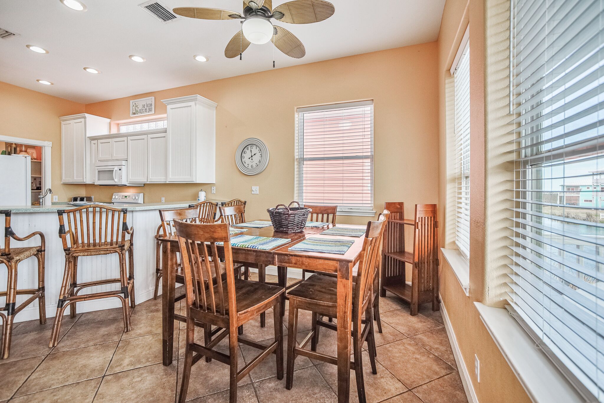 A kitchen with white cabinets, a microwave, and a dining area with wooden chairs and a table.