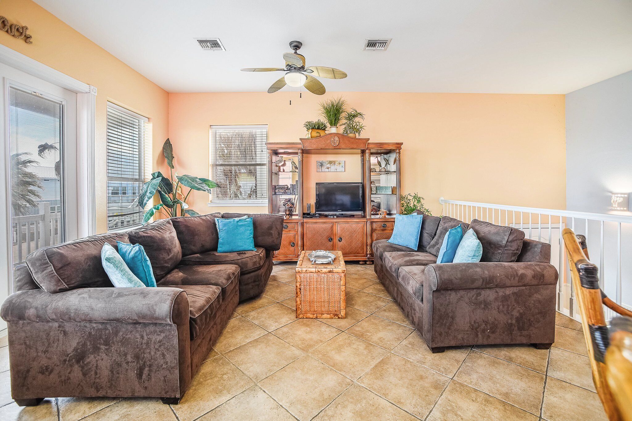A living room with two brown sofas, a wooden coffee table, and a ceiling fan.