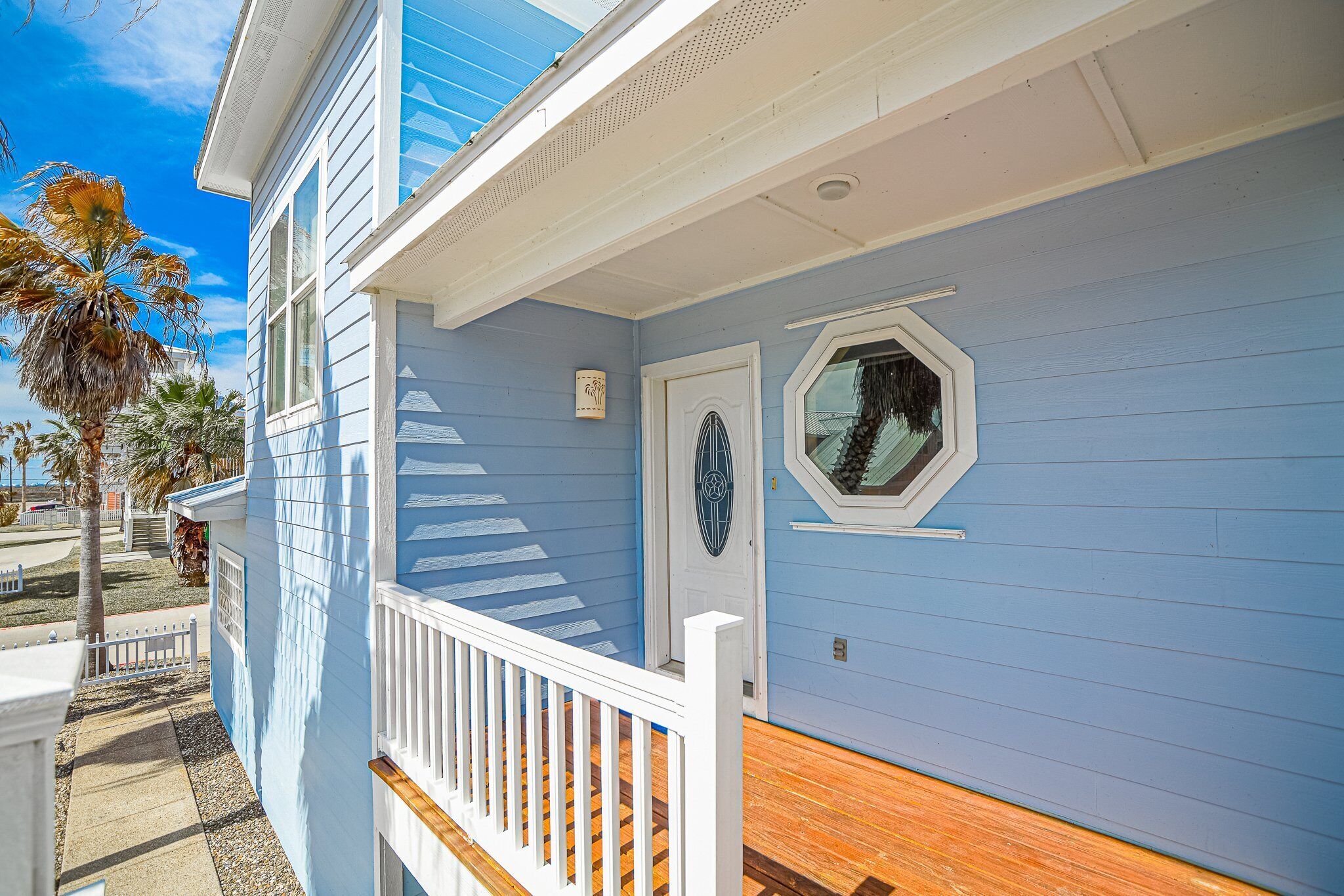A two-story building with a blue exterior, white trim, and a wooden deck.