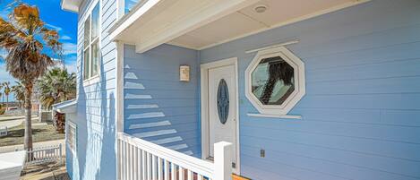 A two-story building with a blue exterior, white trim, and a wooden deck.