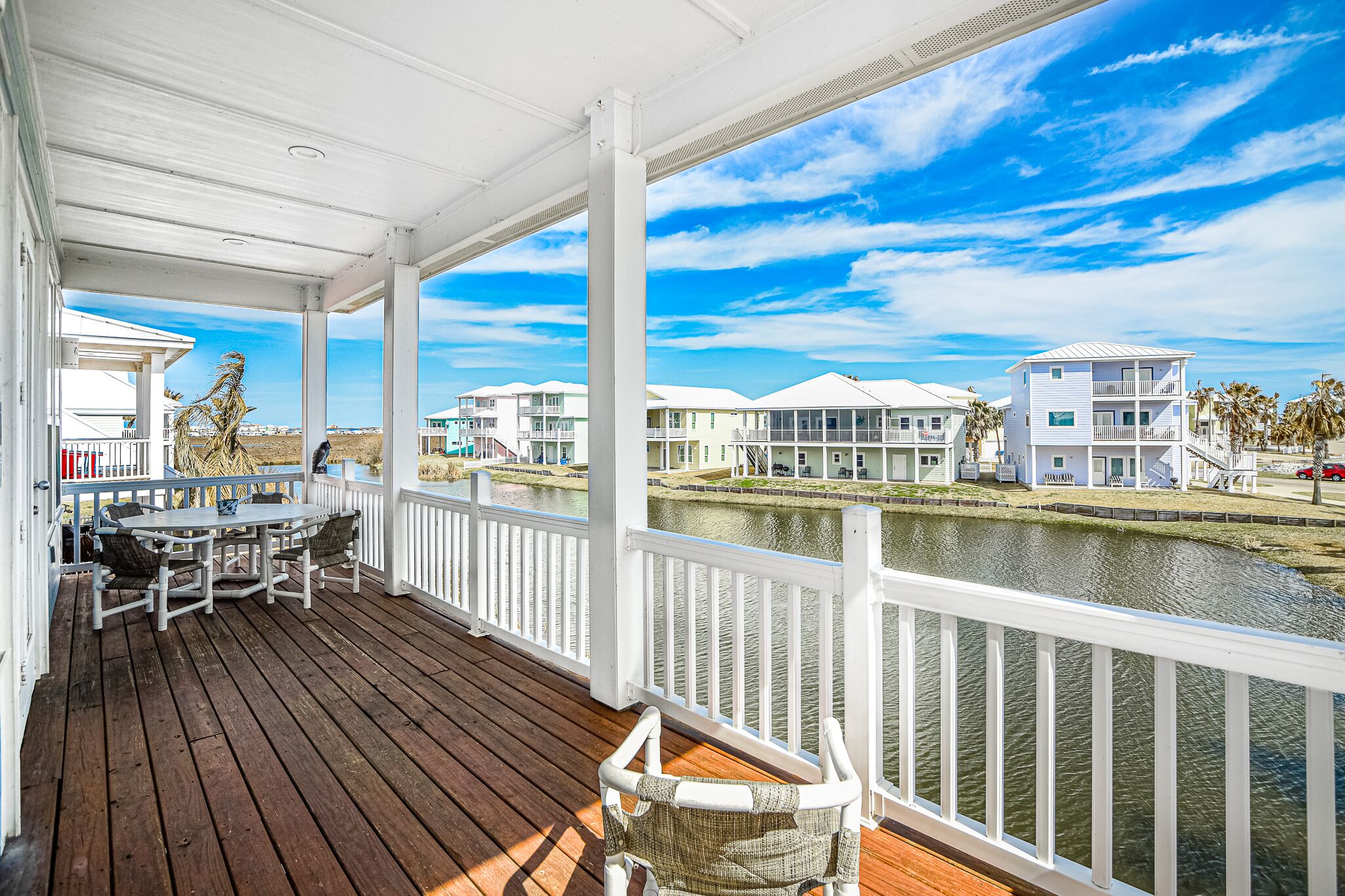 A covered deck with a view of a water body and adjacent buildings.