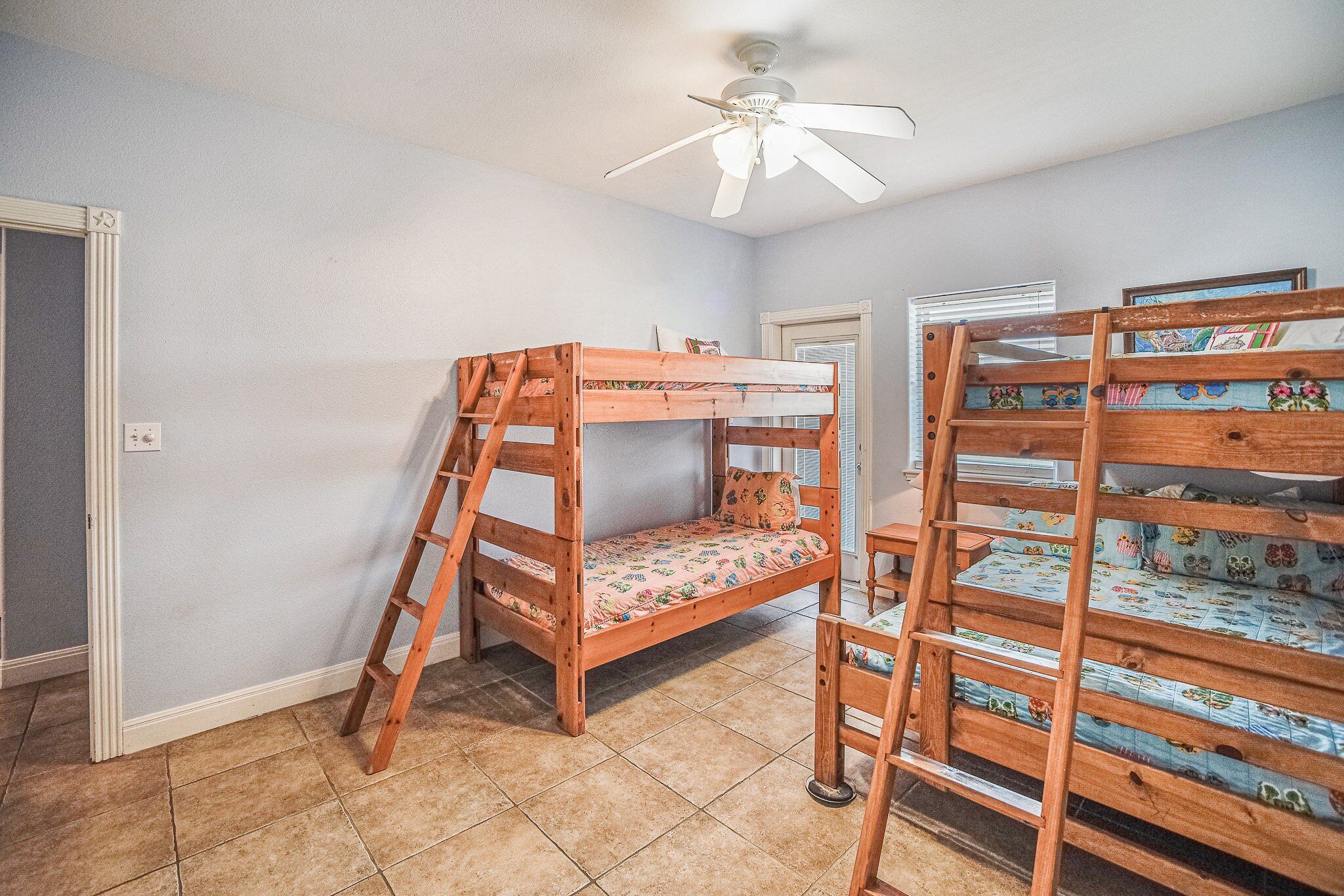 A room with two bunk beds, a ceiling fan, and a door.