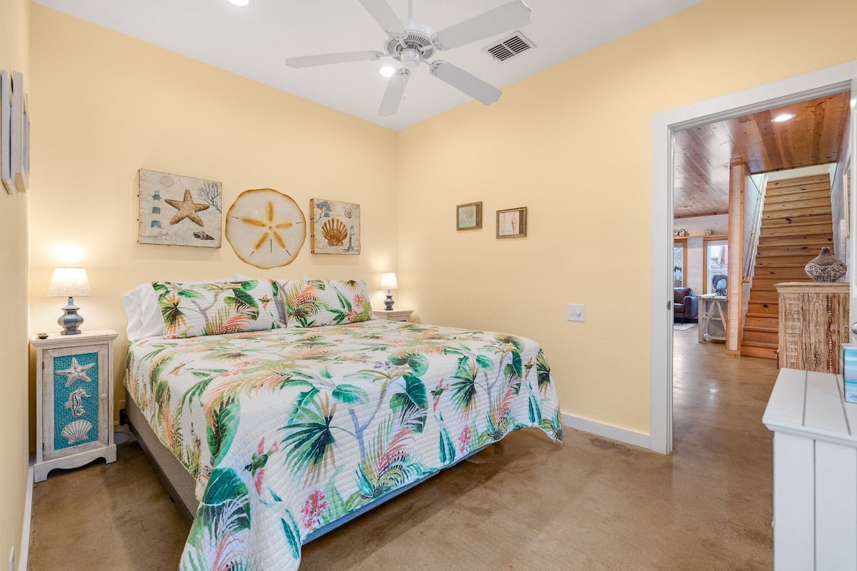 A bedroom with a bed, a ceiling fan, and wall art.