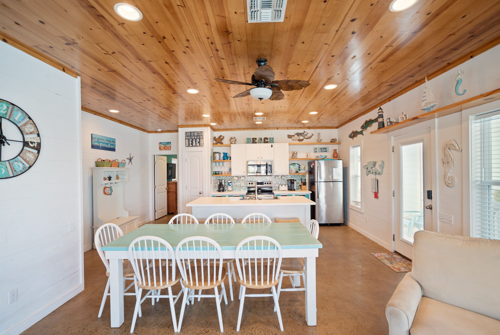 A spacious kitchen with white cabinets, a central island, and a ceiling fan.
