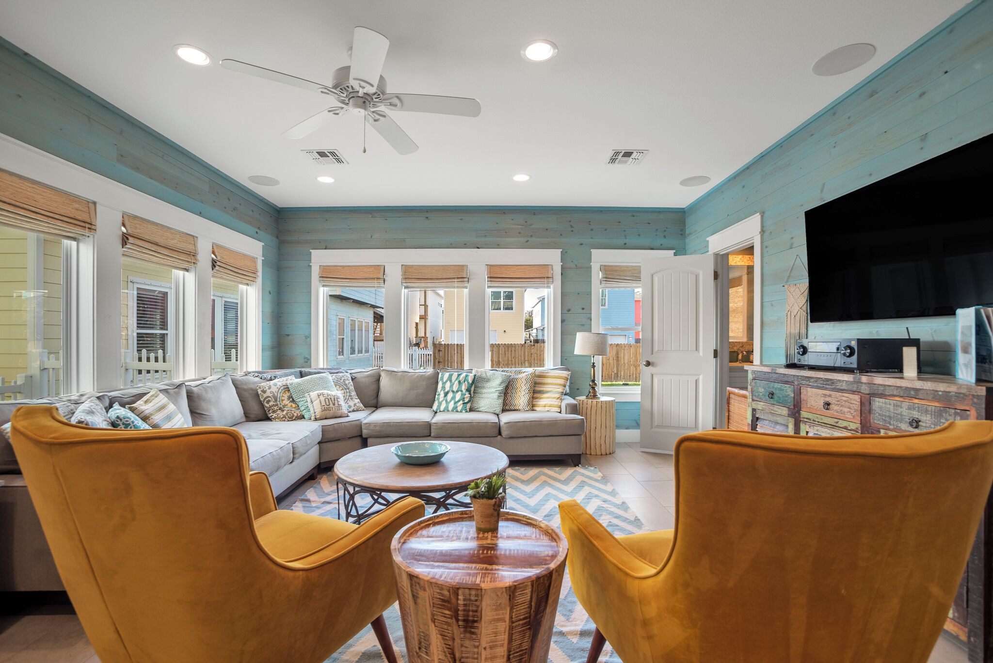 A living room with a sofa, yellow chairs, a coffee table, and a television.