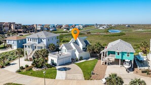 A coastal residential area with houses, a clear sky, and a body of water in the background.