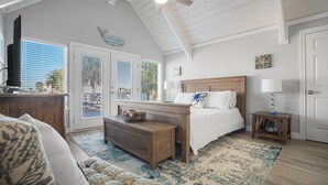A bedroom with a wooden bed, a nightstand, a desk, and a ceiling fan.