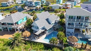A coastal residential area with multiple houses, a central swimming pool, and a dock.