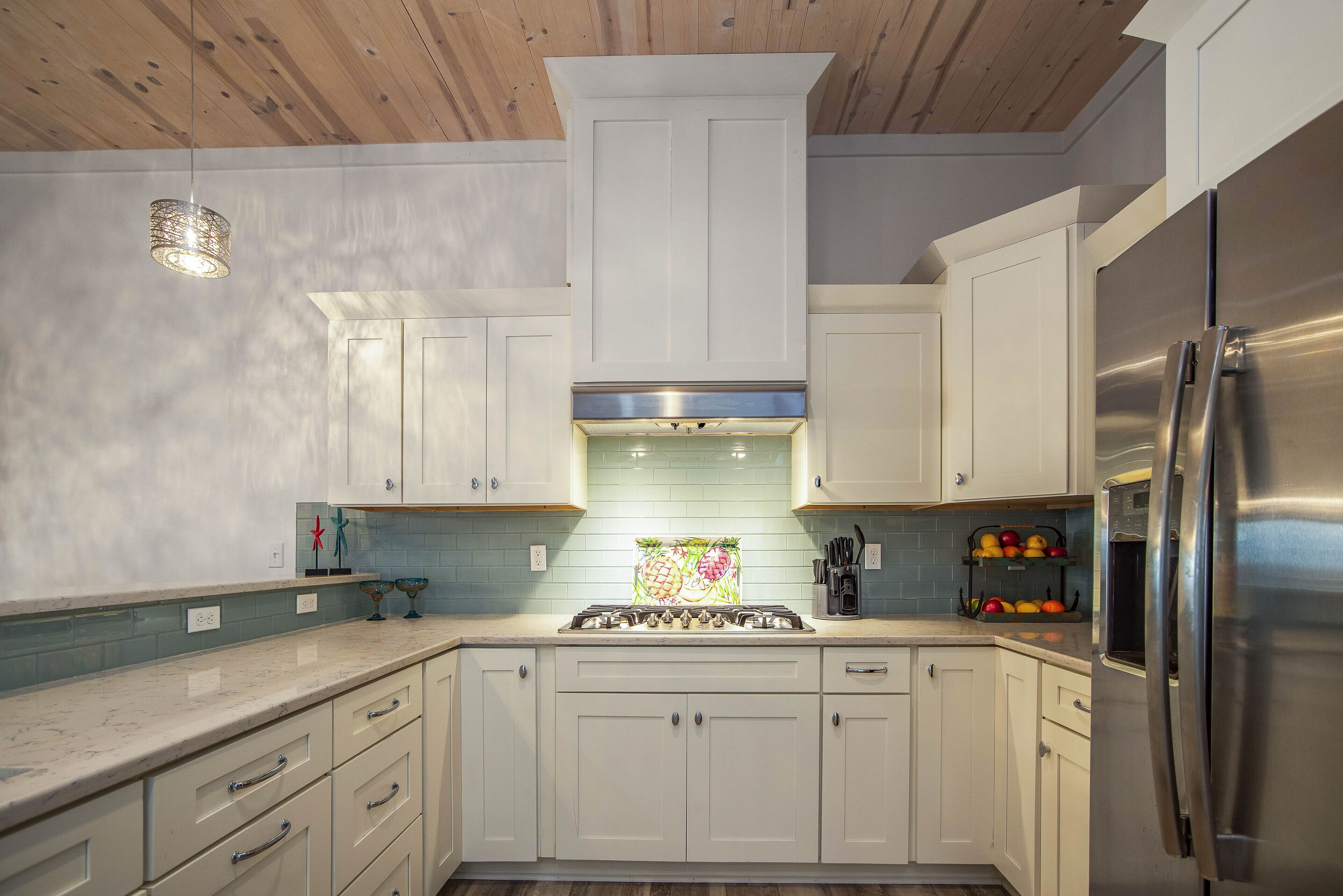 A modern kitchen with white cabinets, a stainless steel refrigerator, and a gas stove.