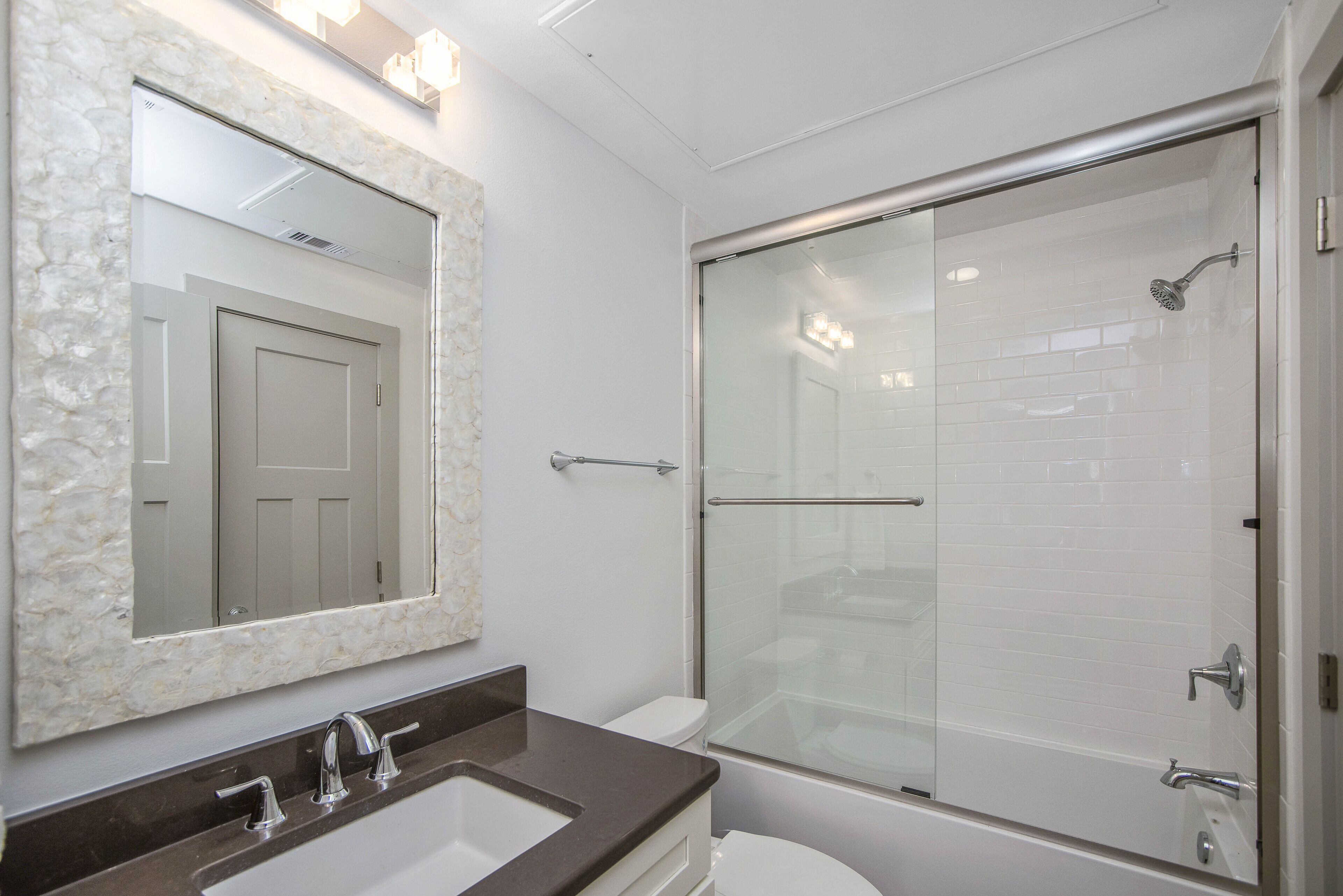 Un baño con lavamanos de mármol, cabina de ducha con vidrio y un inodoro blanco.