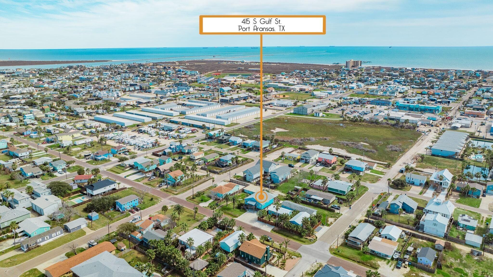 Una vista aerea di una zona residenziale costiera con numerose case e un grande complesso industriale.