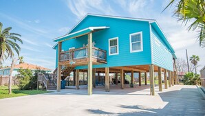 A two-story house with a balcony, wooden deck, and a clear sky.