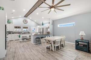 A spacious kitchen with a dining area, wooden flooring, and a ceiling fan.