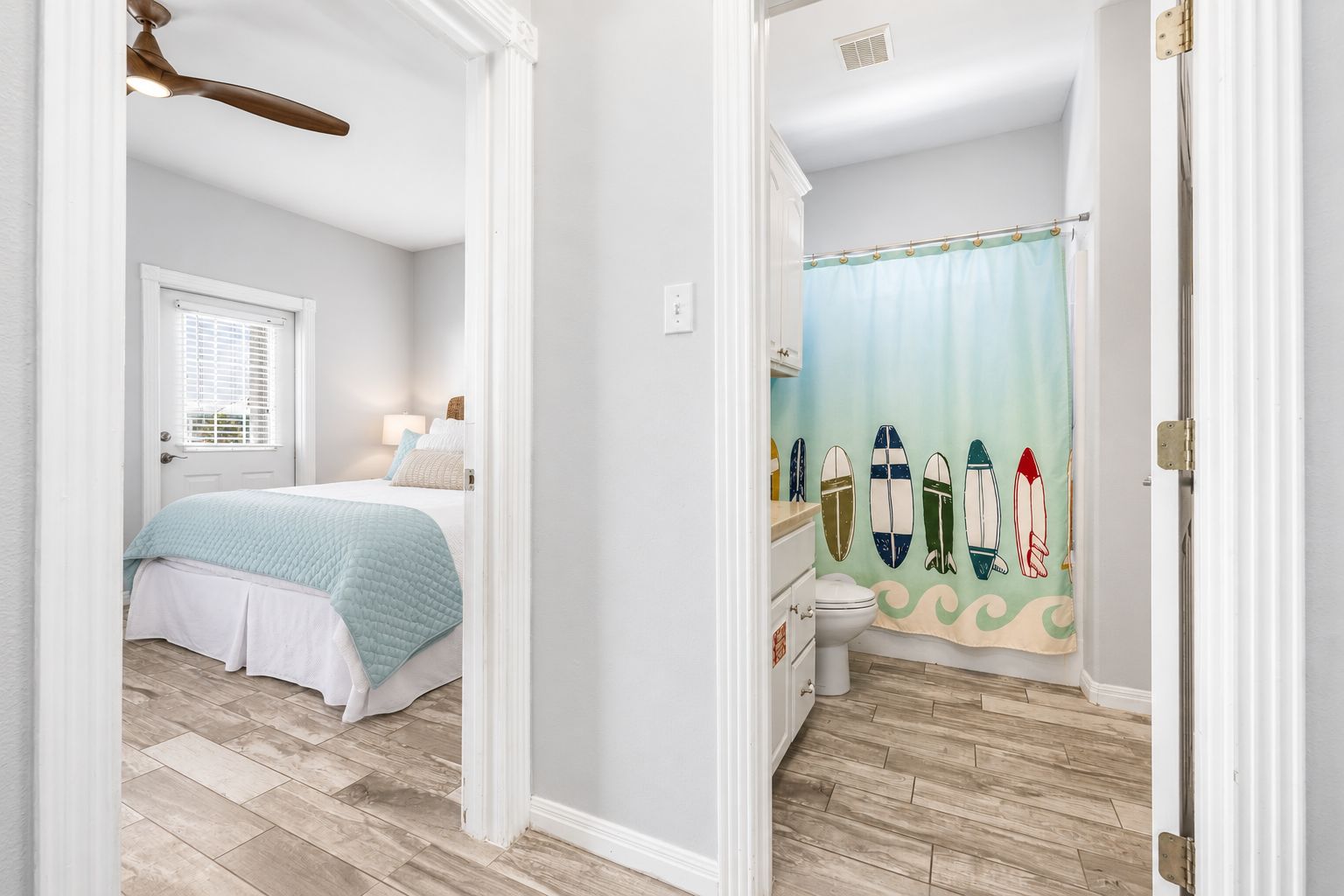 A bedroom with a bed, a nightstand, a window with blinds, and a ceiling fan.