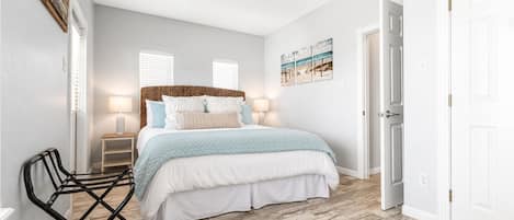 Ein Schlafzimmer mit einem Bett, einem Sessel, einem Deckenventilator und einer Tür.