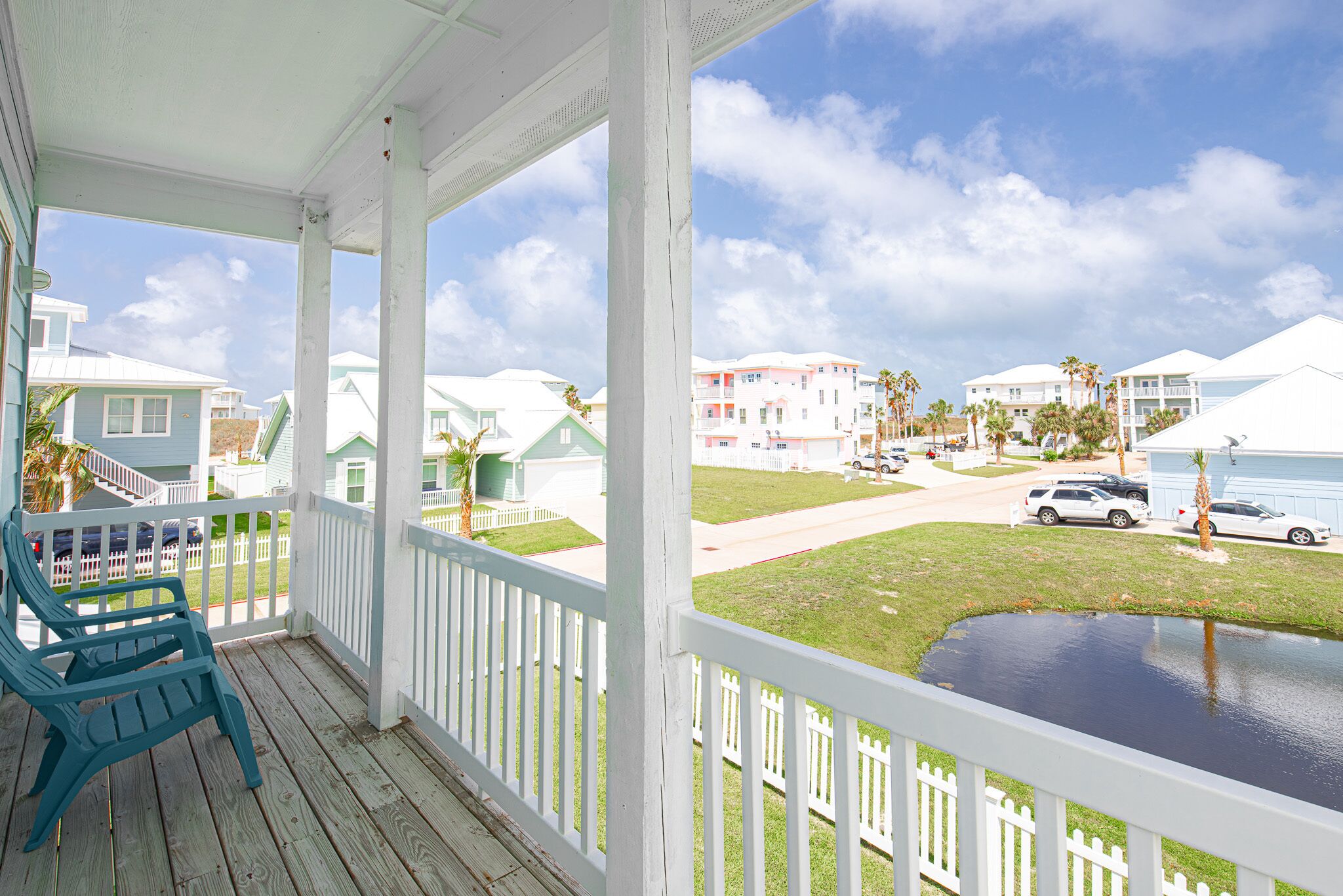 A porch with a view of a residential area, including houses and a road.