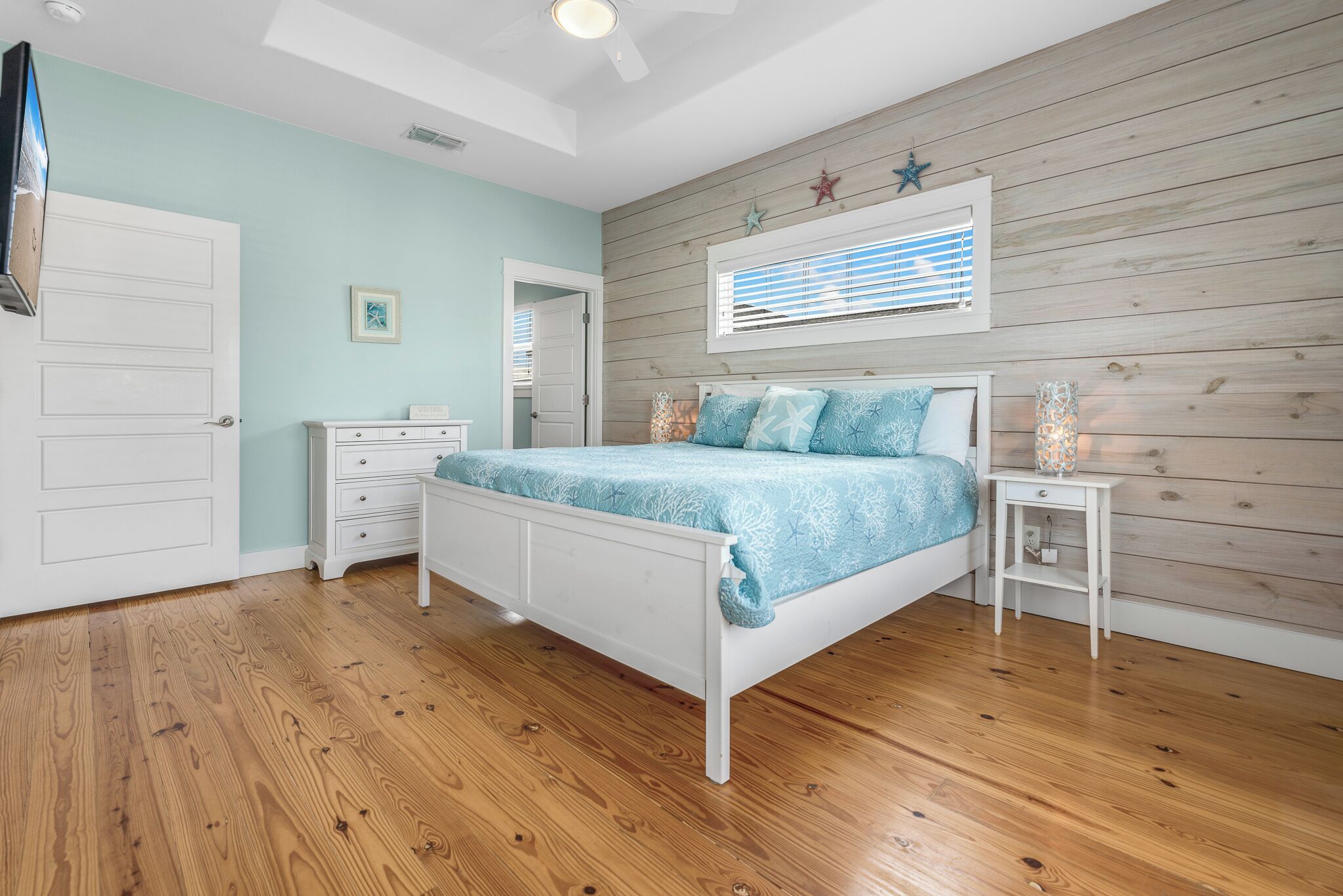 A bedroom with a bed, a nightstand, a dresser, and a window with blinds.
