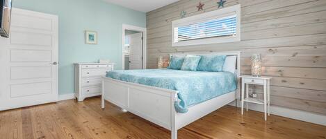 A bedroom with a bed, a nightstand, a dresser, and a window with blinds.